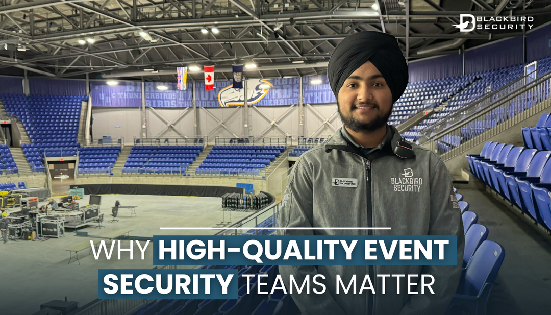 5 Reasons to Hire an Expert Event Security Team for Your Next Event. A Blackbird Security event security guard wearing a grey zippered jacket stands in a large, empty stadium while staff members set up a stage in the background.