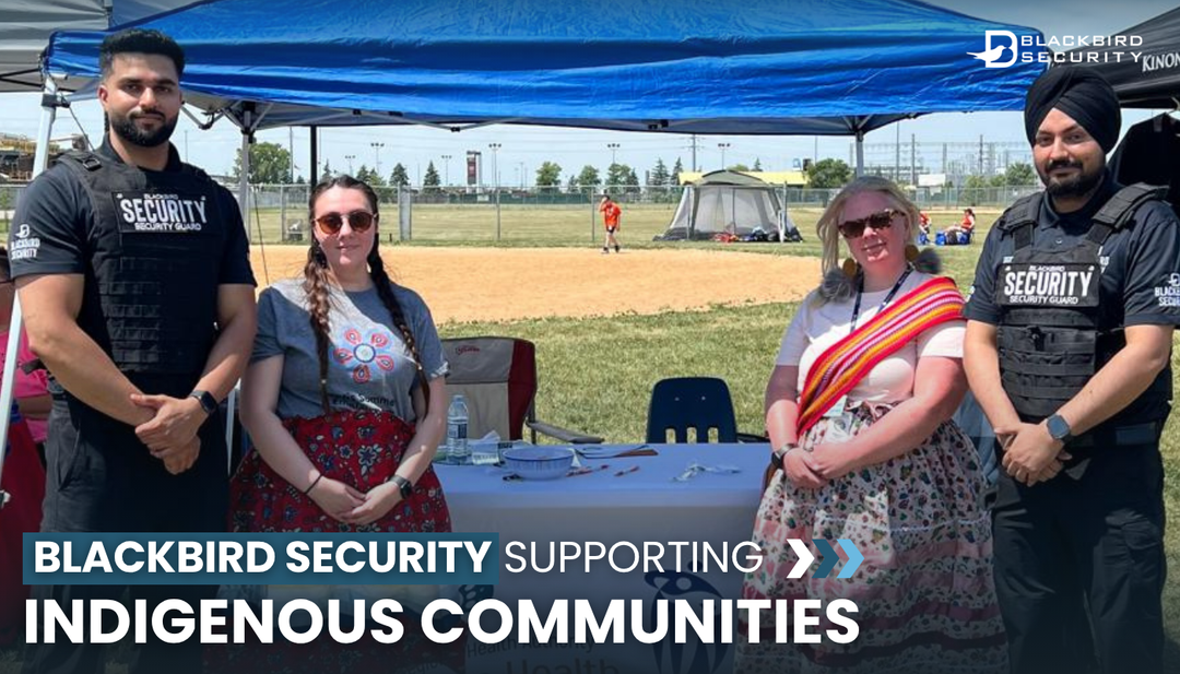 Two Blackbird Security guards stand under a blue tent with two Indigenous women at the Circles for Reconciliation event in Winnipeg.