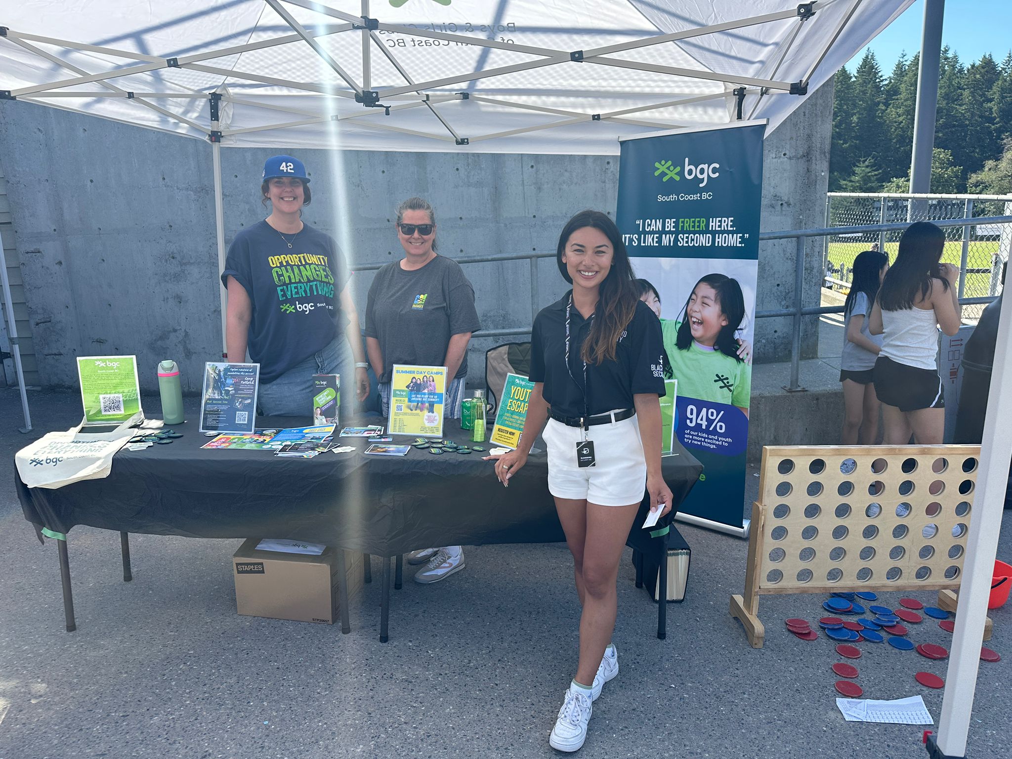 People standing under pop up tent with brochures on table