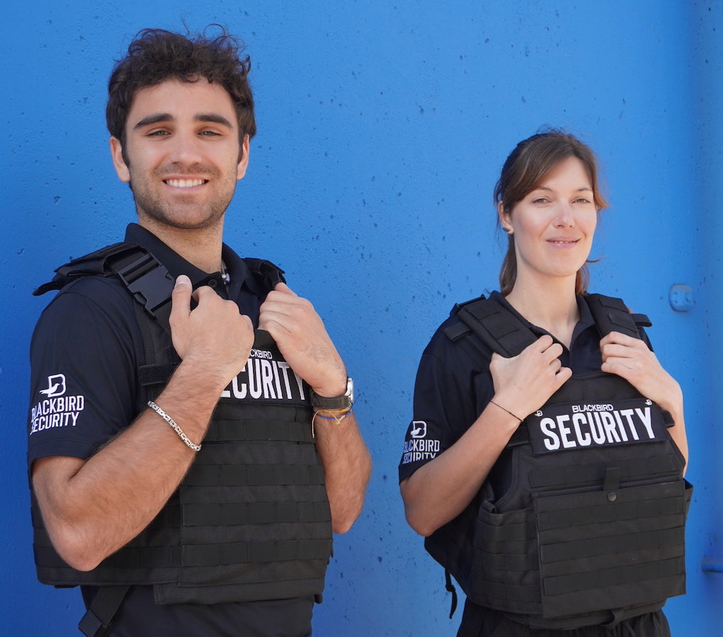 Two uniformed Calgary security guards standing outside a business with a solid green wall behind them