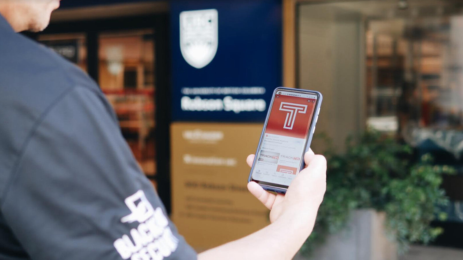 Close up of security guard holding a mobile device showing Tracktik technology on the screen