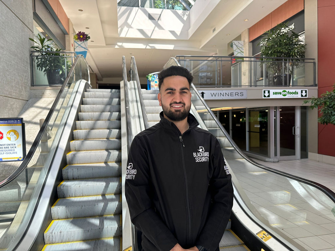 Blackbird Security officer in uniform at bottom of escalator in shopping mall
