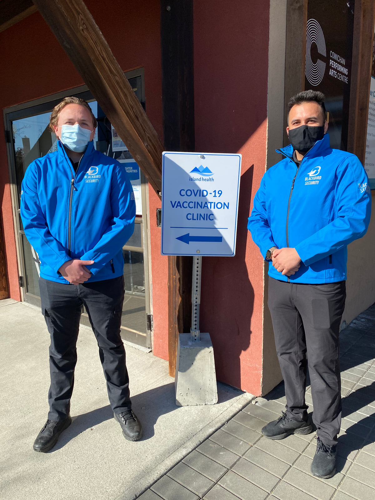 Person wearing a blue jacket with a COVID-19 vaccination clinic sign in the background.