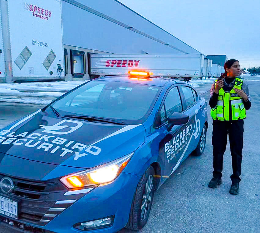Four Blackbird security in front Mobile patrol car at Speedy warehouse