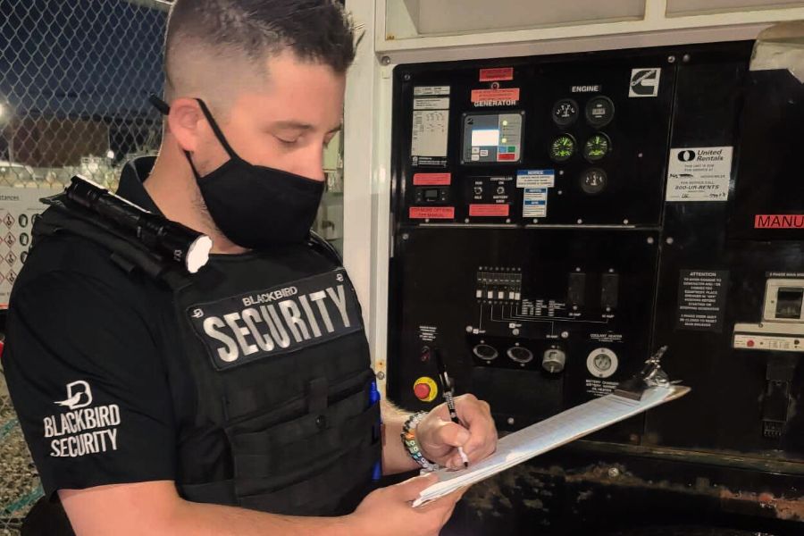 Uniformed Blackbird security guards standing in front of control panel with clipboard