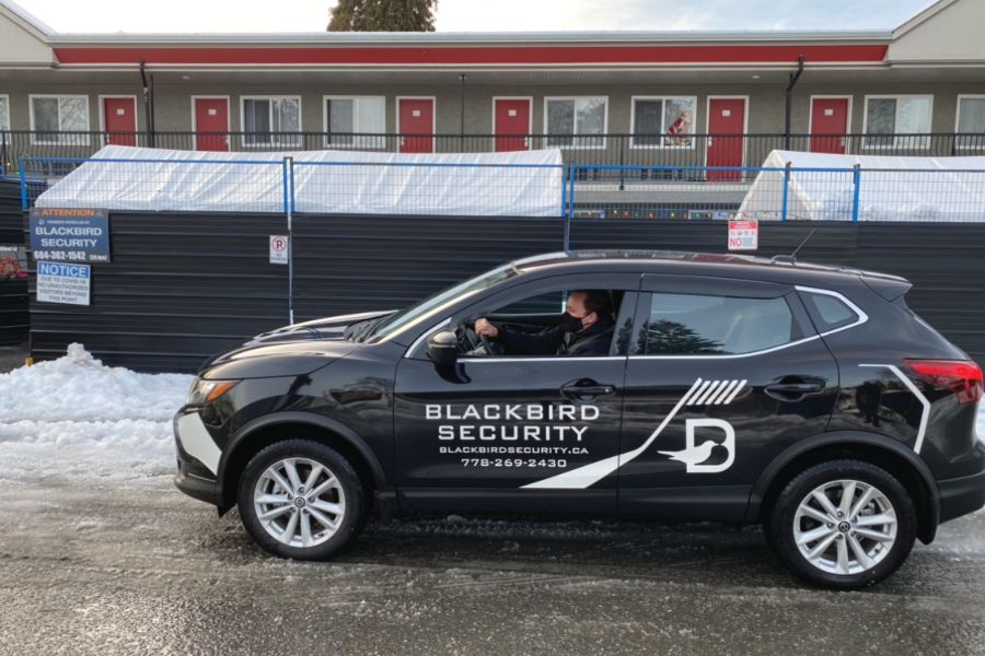 Blackbird security guard driving Mobile patrol car in front of motel