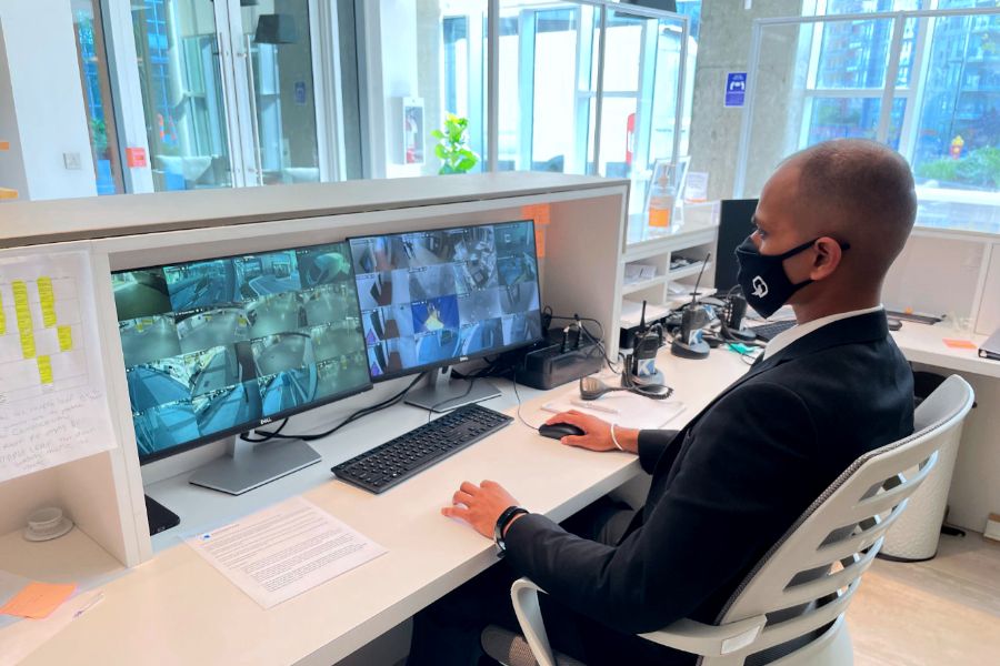 Blackbird security guard sitting at concierge desk in front of two security camera screens