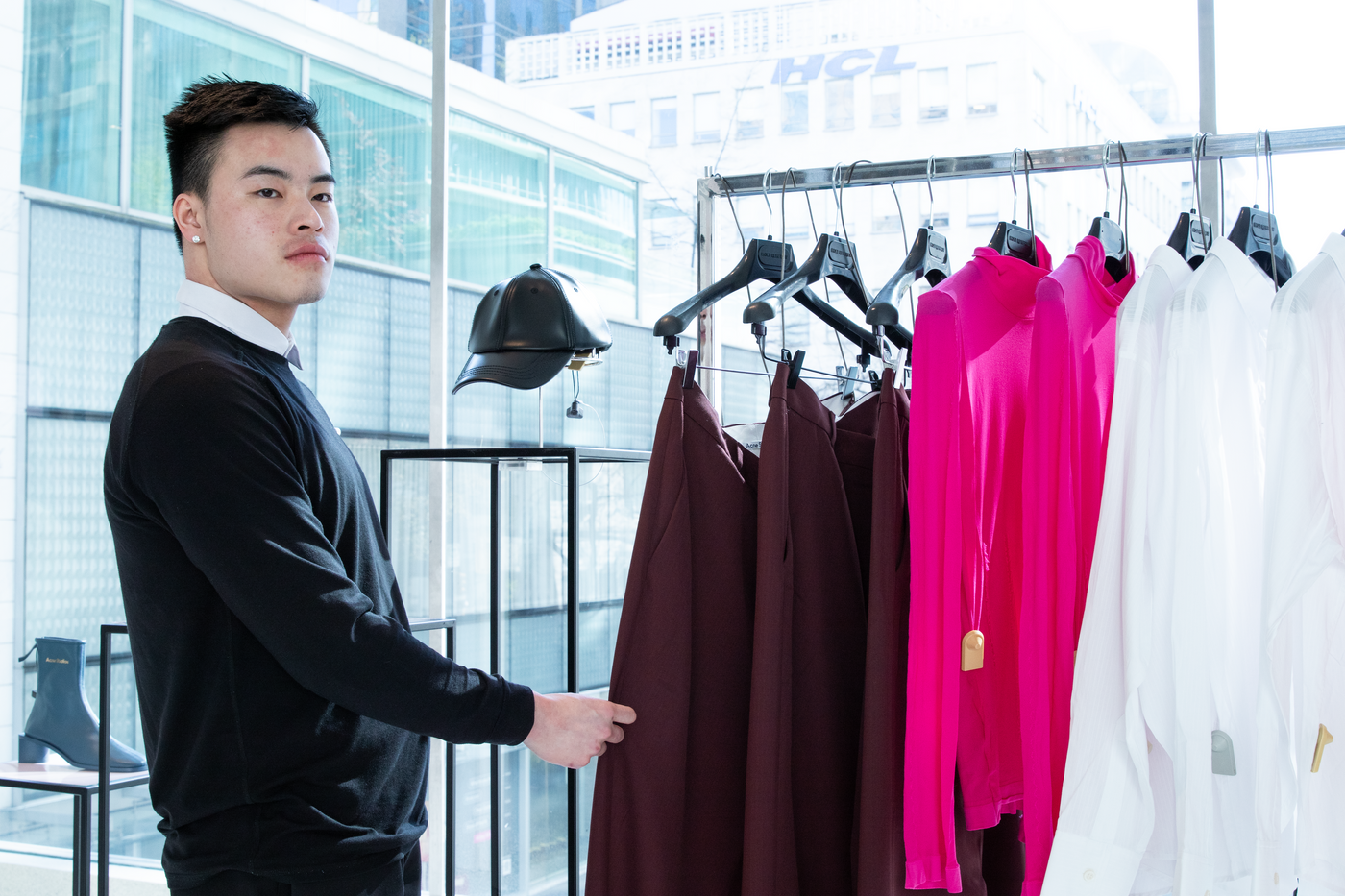 A loss prevention professional in a suit and tie ensures retail security by blending into the backdrop. He peruses clothing while keeping an eye on his surroundings