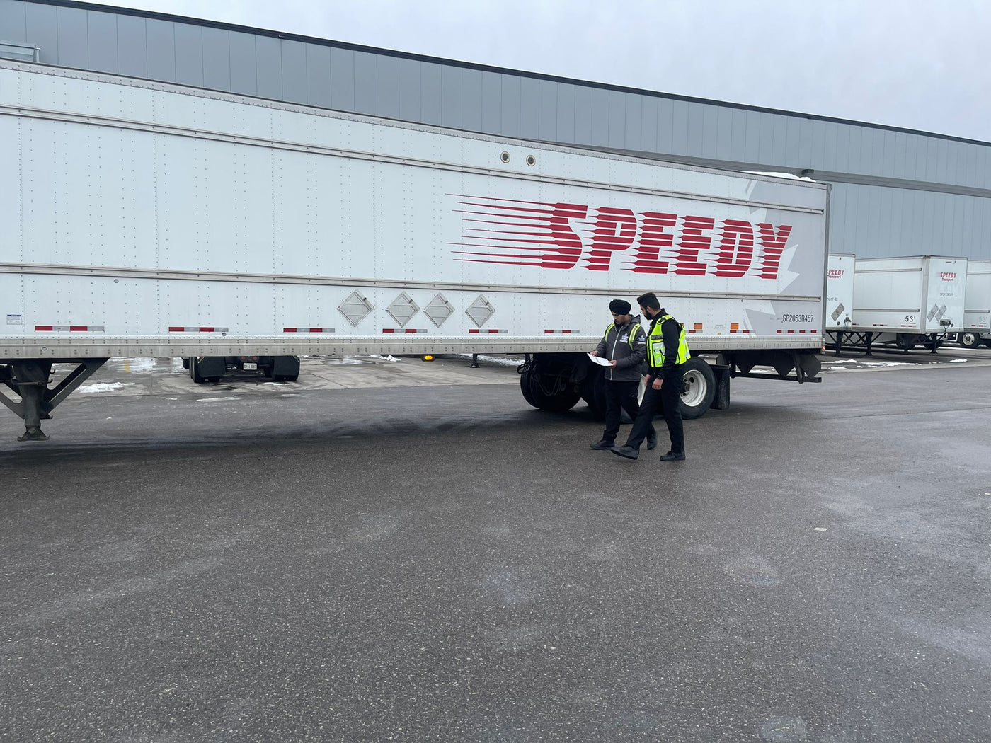 An industrial site security guard in high-vis gear stands in front of a cargo truck