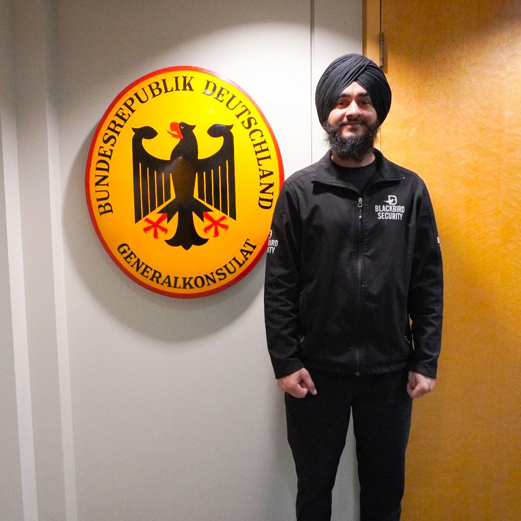 Uniformed Blackbird security guard in front of German consulate sign