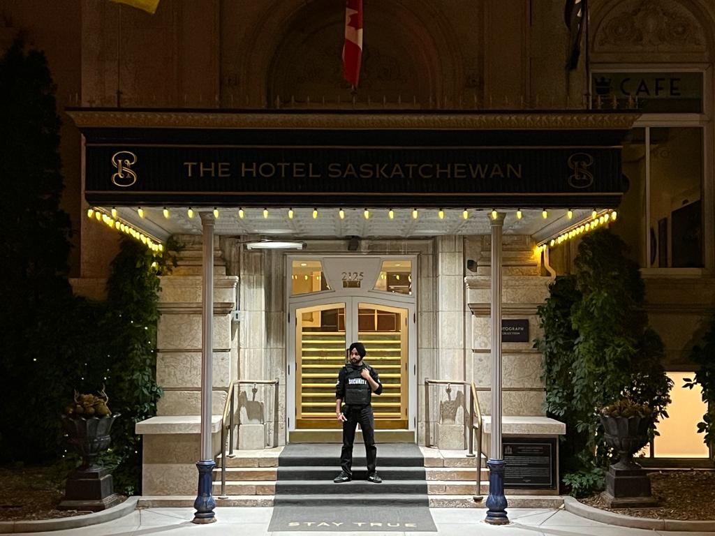 Uniformed Blackbird security guard standing in front of hotel building entrance