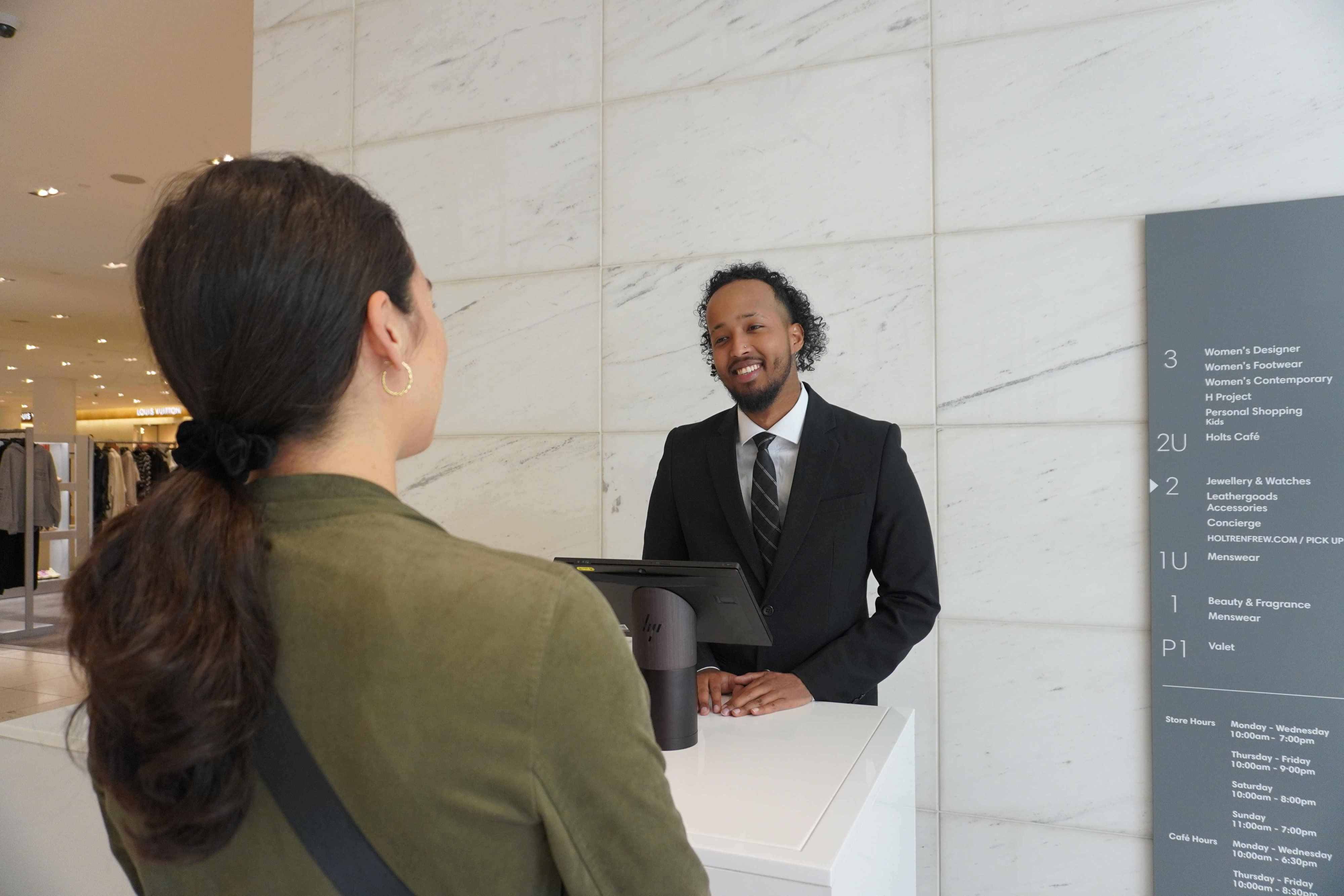 Plained Clothes Blackbird security guard speaking with woman at concierge desk