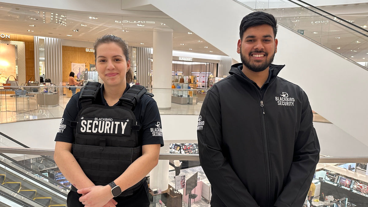 1 female and 1 male uniformed blackbird security guards in shopping mall