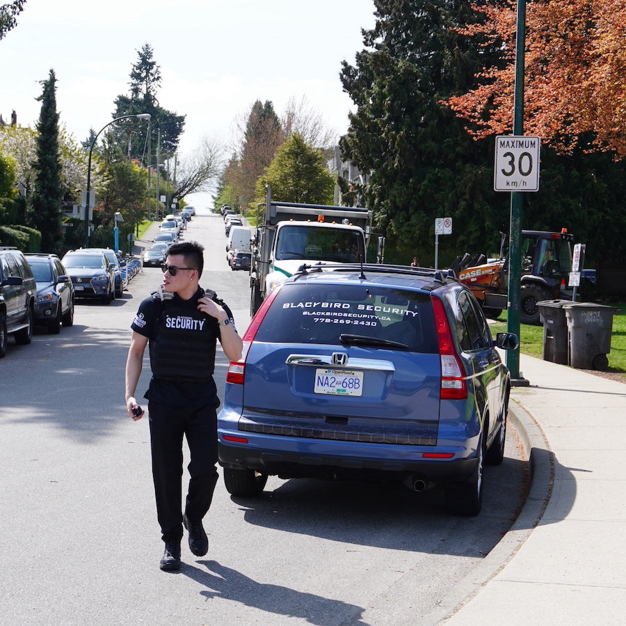 Blackbird Security guard is walking away from their parked vehicle on the street