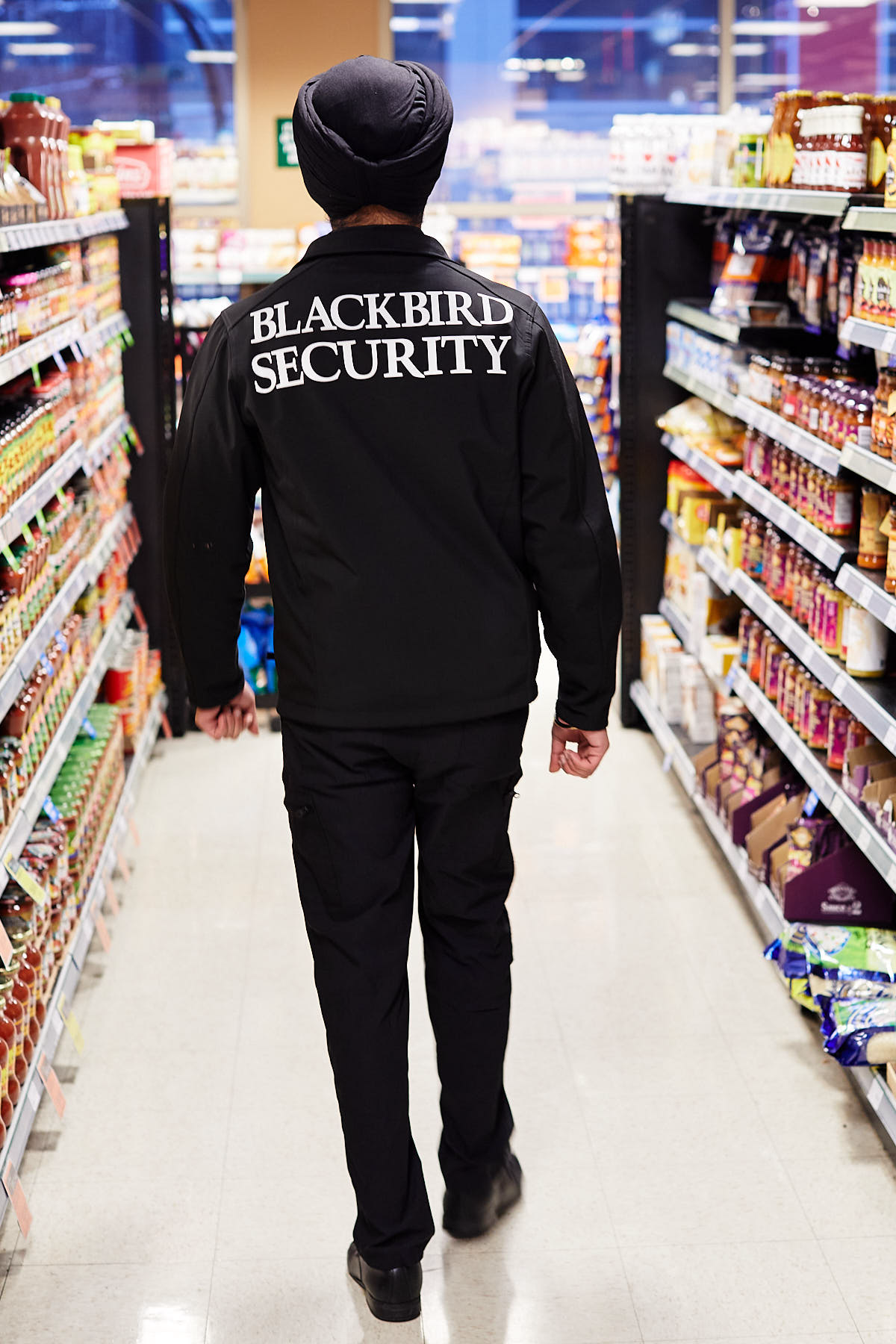 Blackbird Security Uniformed security guard walking down grocert store isle