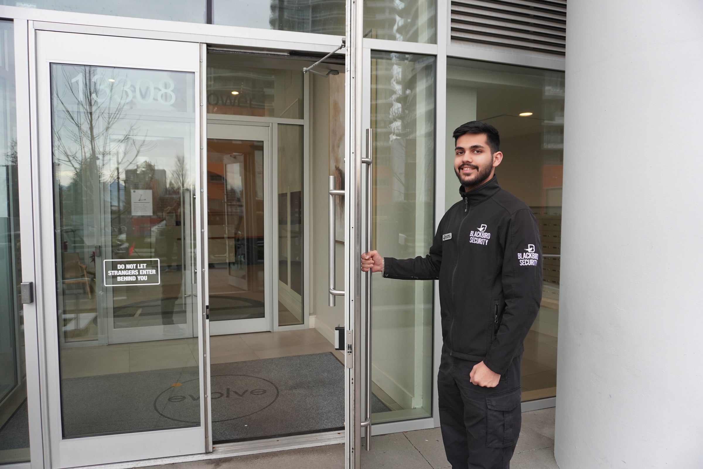 Uniformed Blackbird security guard opening door