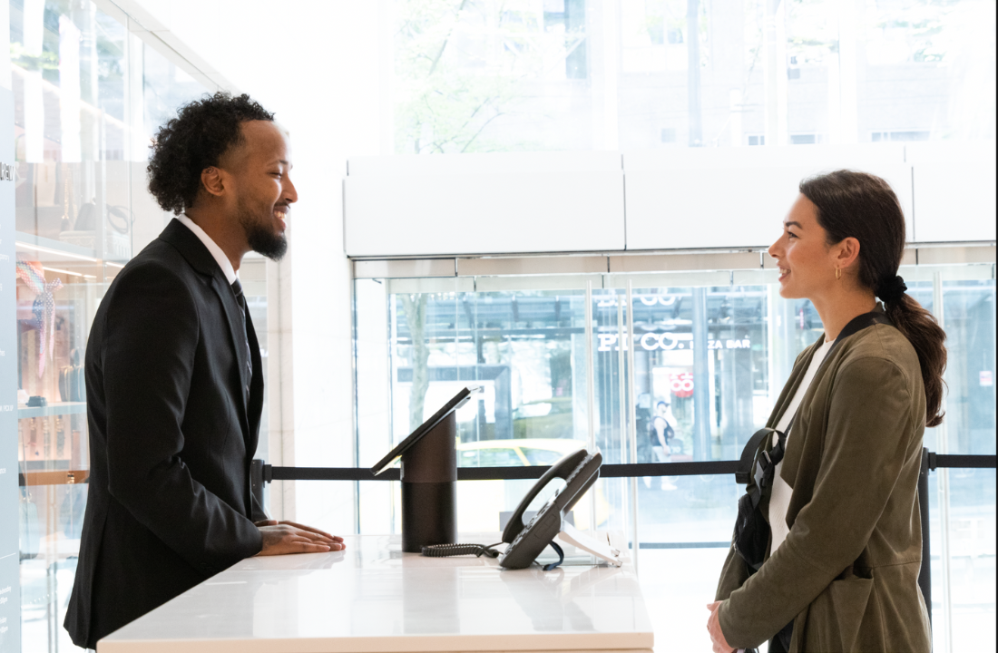 A security guard at a hotel service desk greeting a client