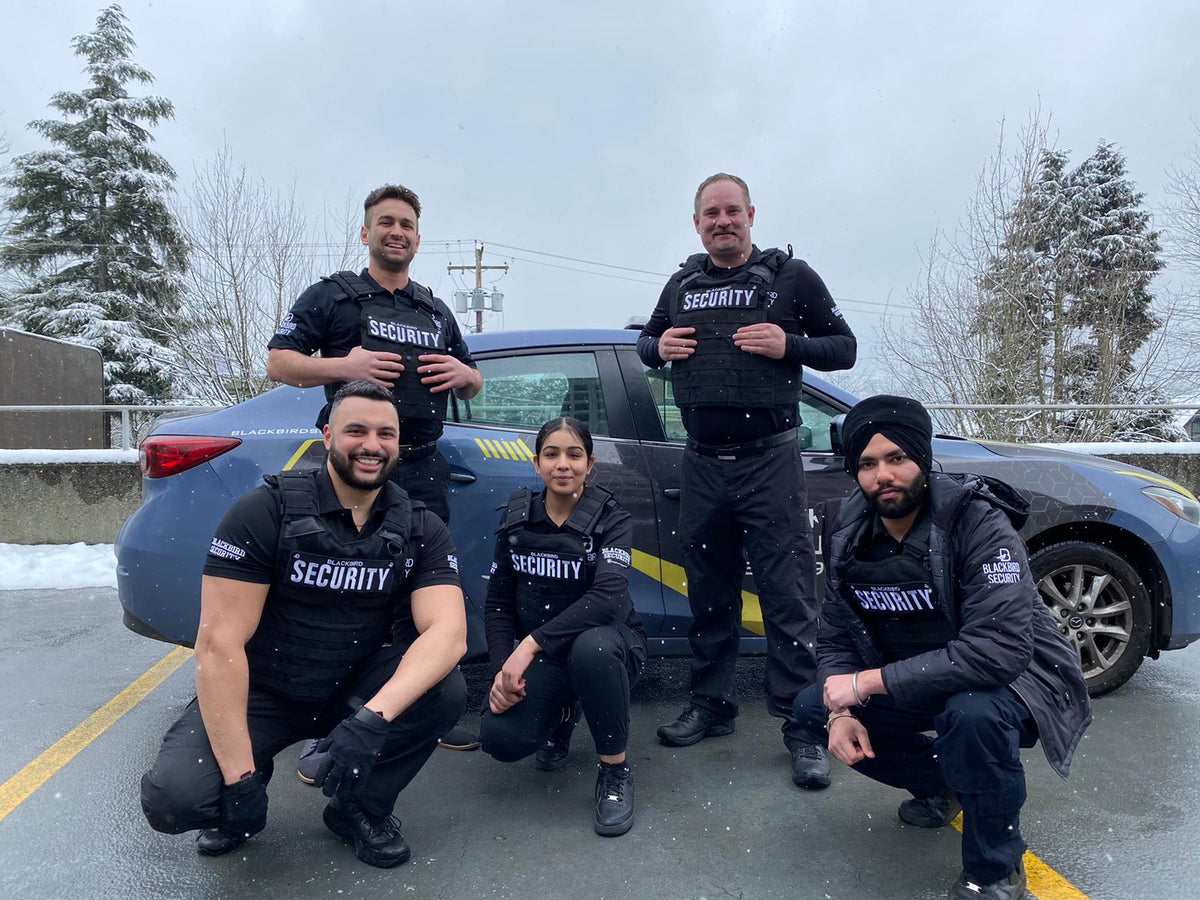 Blackbird Security mobile patrol team in uniform outside, next to a branded Blackbird mobile patrol vehicle 