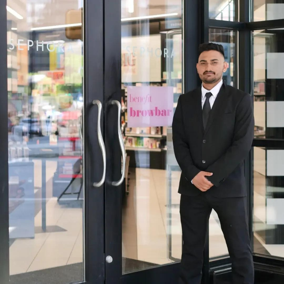 suit and tie security guard standing outside of a glass door of a Sephora store