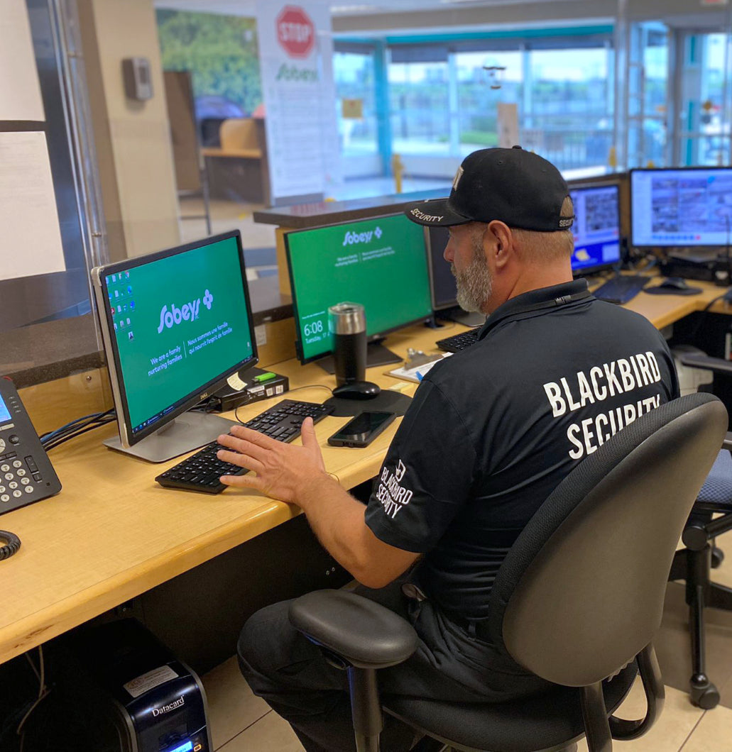 warehouse concierge security guard sitting in front of bank of monitors at desk