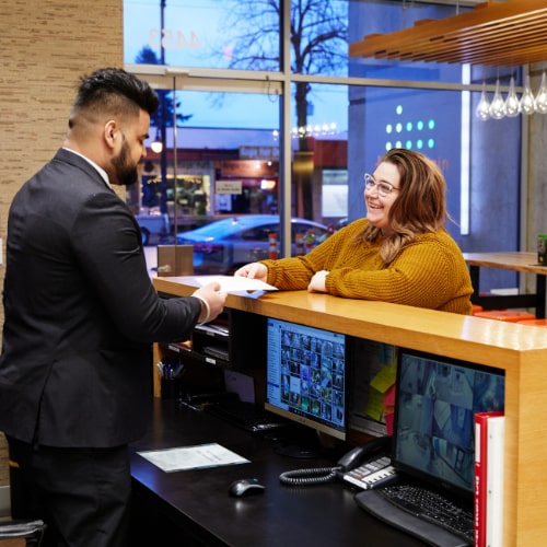 Blackbird concierge security guard behind a desk handing a woman a paper