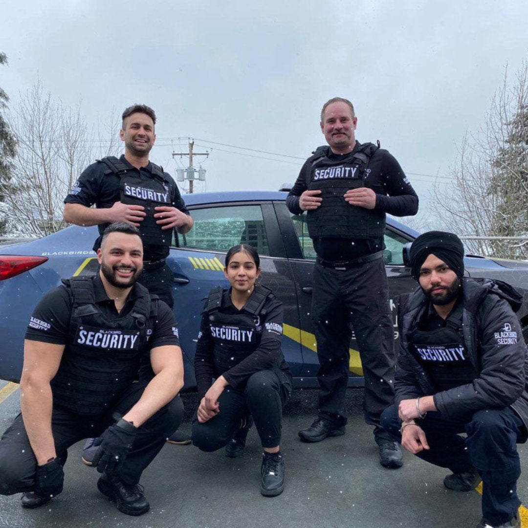 Blackbird Security uniformed security guards outside of a mobile patrol car in the snow