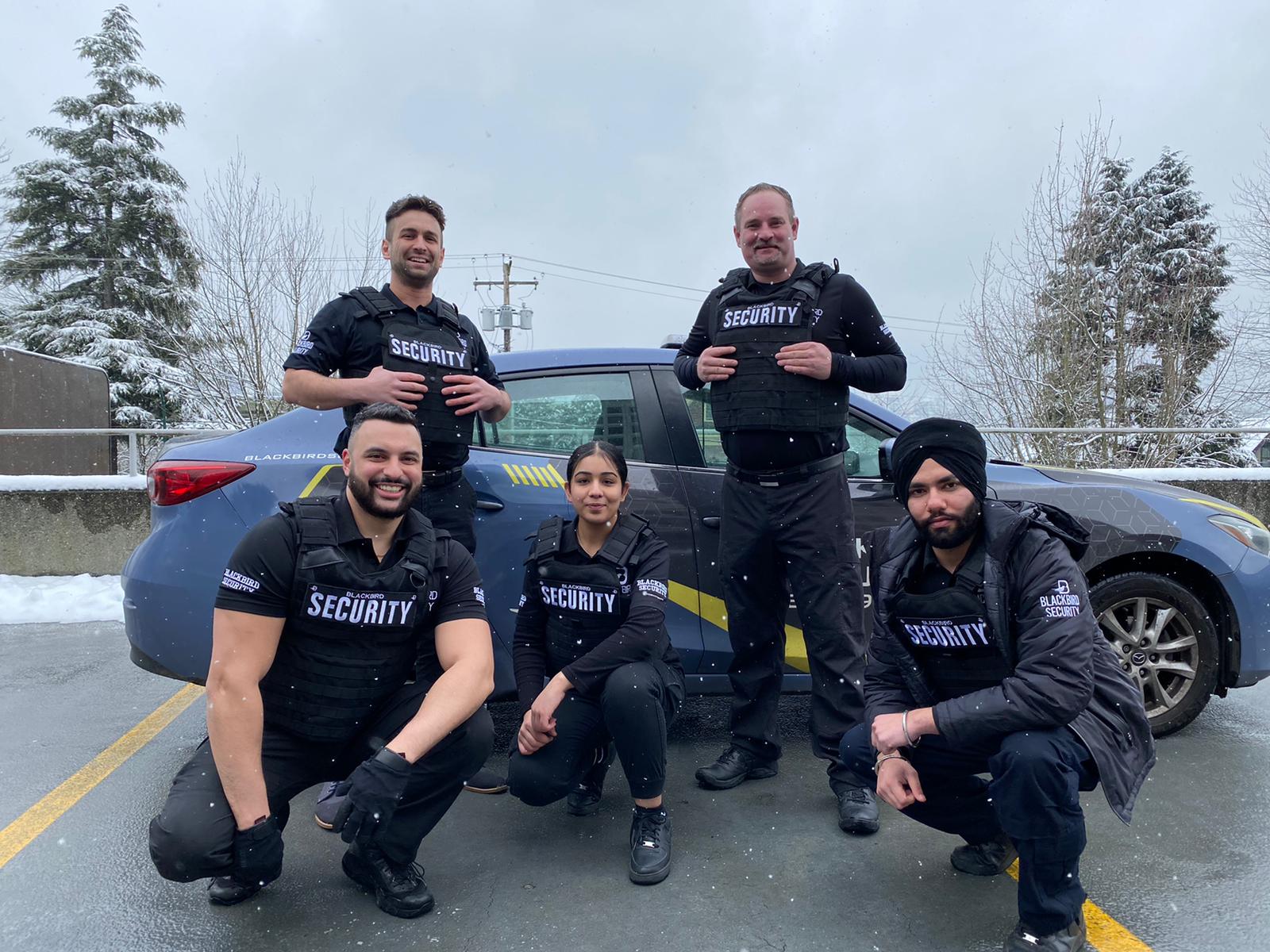 Group of uniformed Blackbird Security mobile patrol guards in front of a car